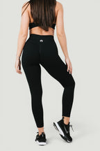 A N A M E black midnight high-waist leggings with sculpting fit and logo detail, worn by a model in a studio setting.