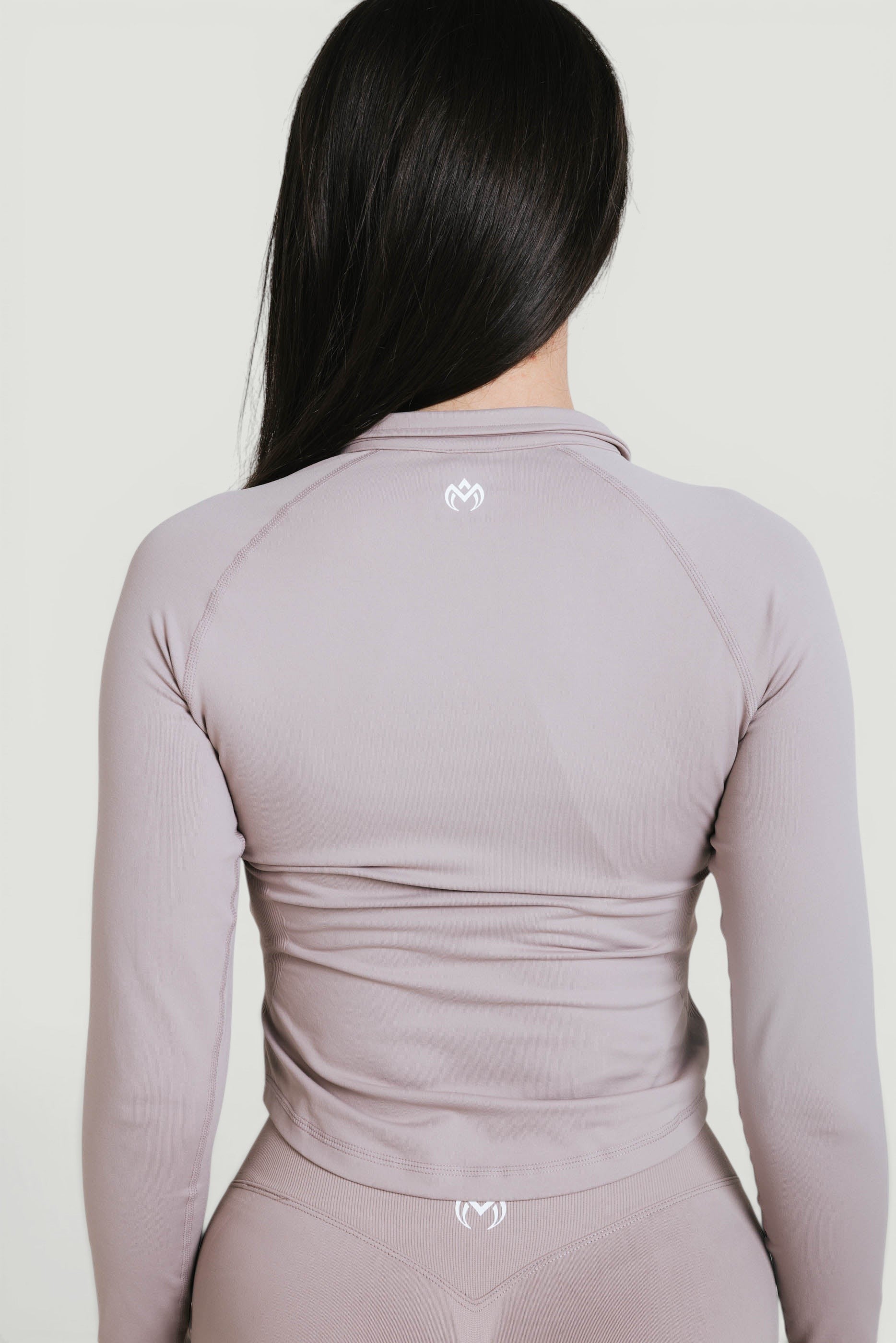 A N A M E Core Jacket in Mocha Cappuccino, a long-sleeve performance top with a feminine fit and subtle logo detail on the back.