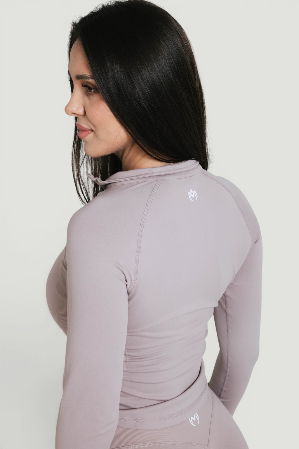 A N A M E Core Jacket in Mocha Cappuccino, a long-sleeve performance top with a high neck worn by a woman.