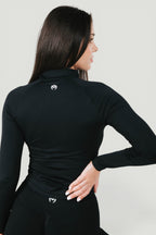 A N A M E Core Jacket in black, a long-sleeve performance top with a mock neck and subtle logo detail on the back.