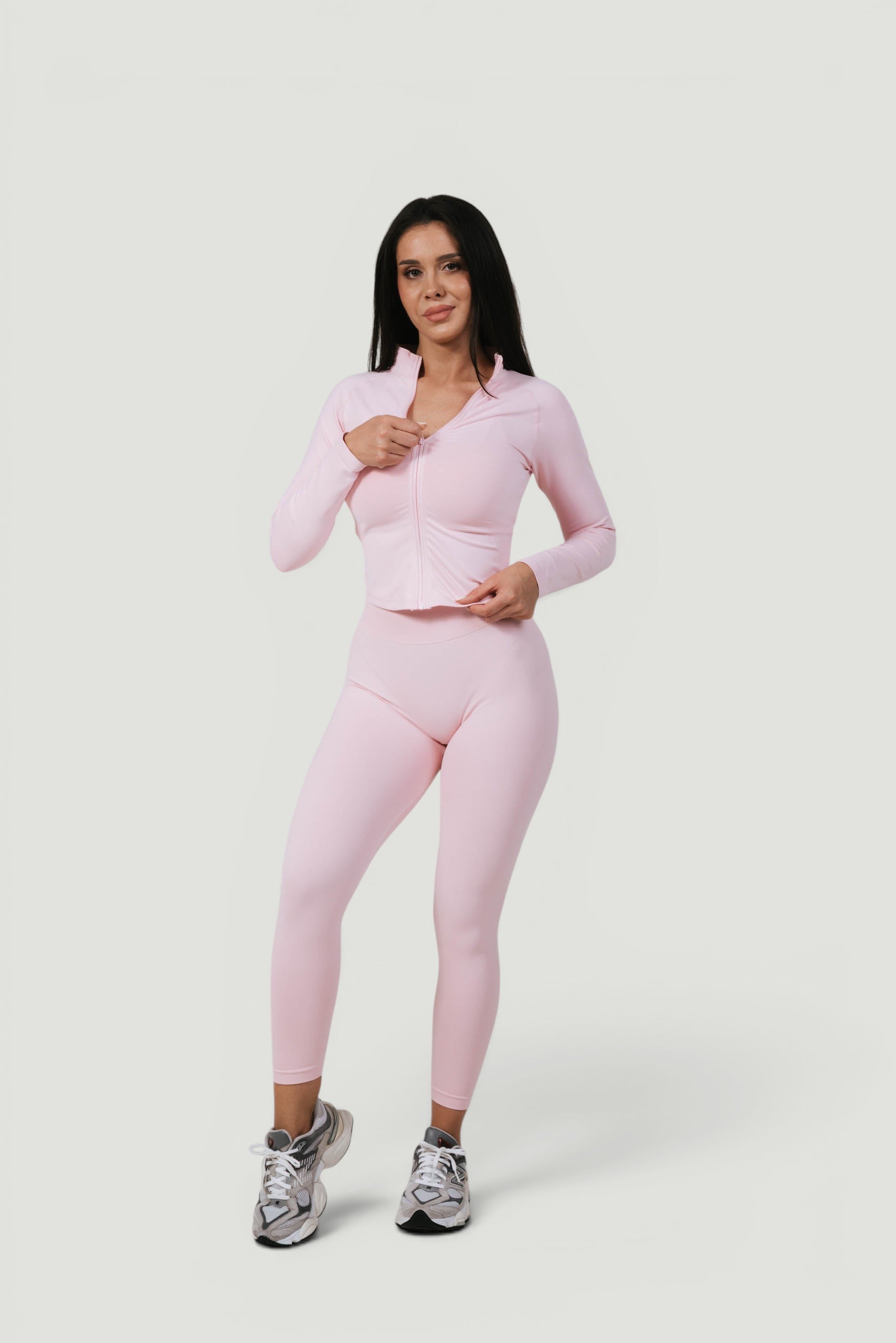 A N A M E Core Jacket in pink rose, a performance long-sleeve zip-up worn by a model with matching leggings.