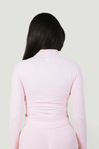 A N A M E Core Jacket in pink rose, a long-sleeve performance top with a mock neck and subtle back logo detail.