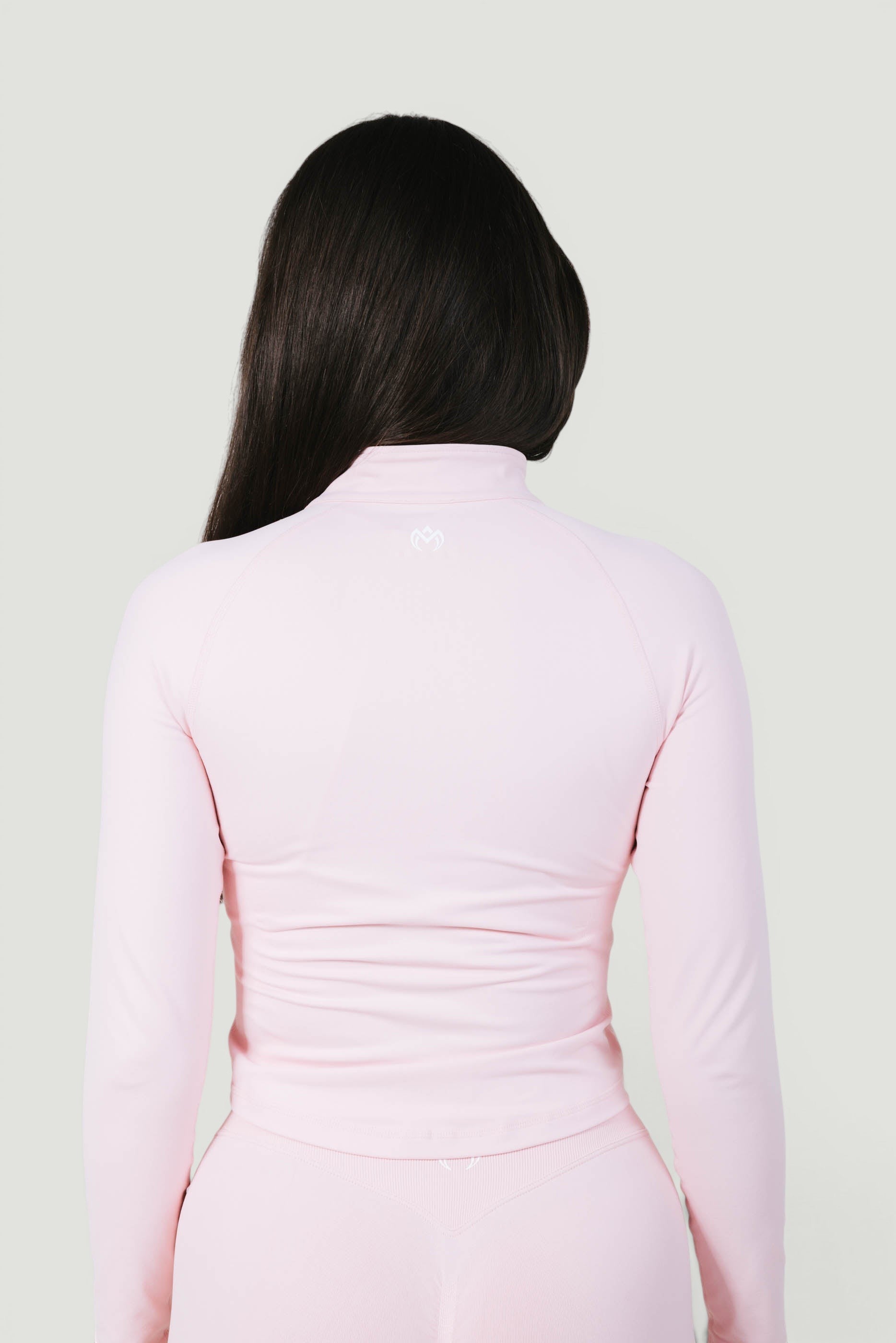 A N A M E Core Jacket in pink rose, a long-sleeve performance top with a mock neck and subtle back logo detail.