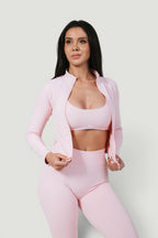 A N A M E Core Jacket in pink rose, a long-sleeve performance zip-up worn by a model over a matching sports bra.