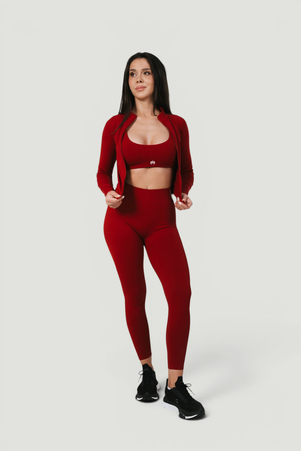 Model wearing A N A M E red wine Core Jacket, matching sports bra, and leggings for a versatile athletic look.