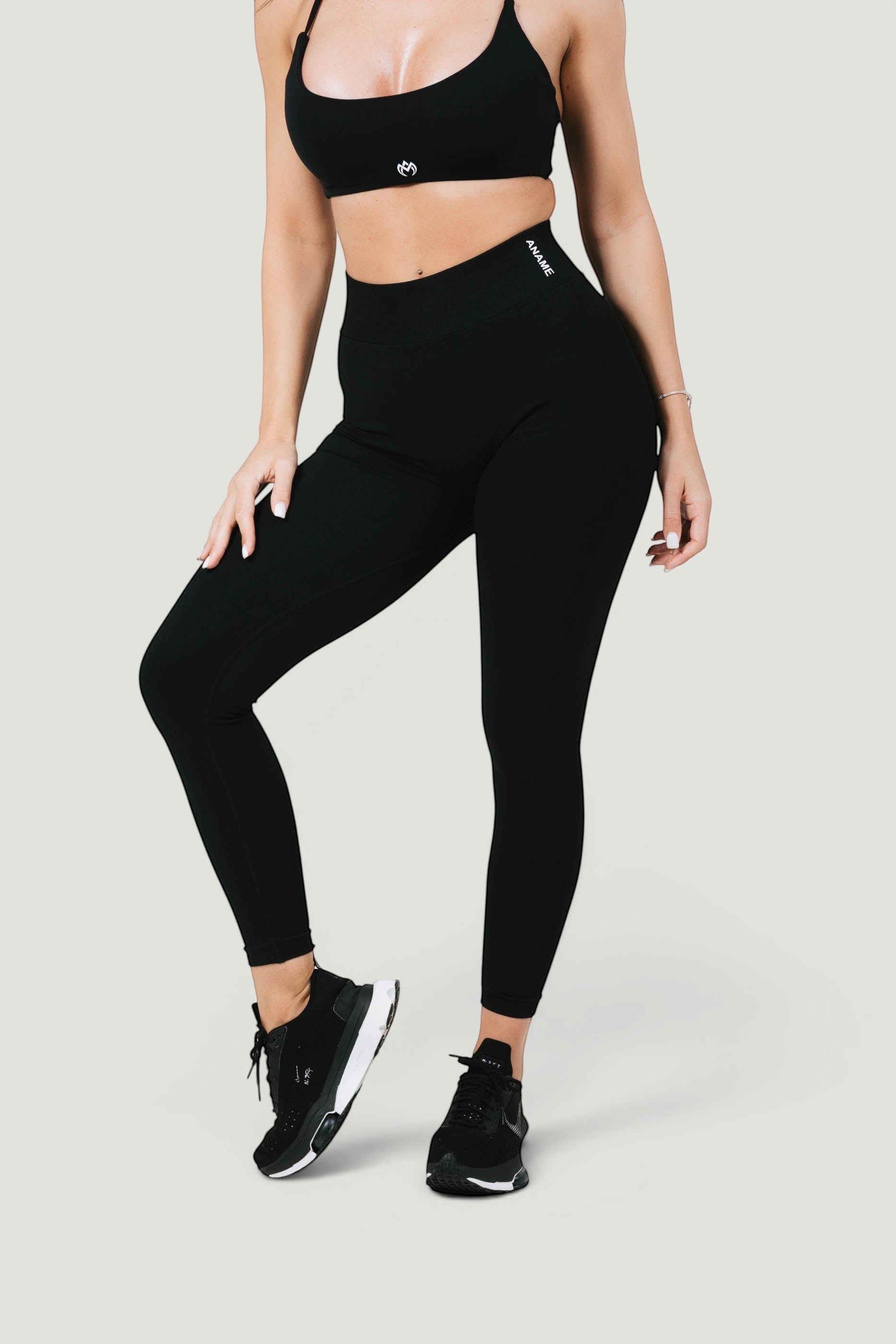 A N A M E black midnight high-waist leggings on a model, featuring a sculpted fit and branded waistband for athletic wear.