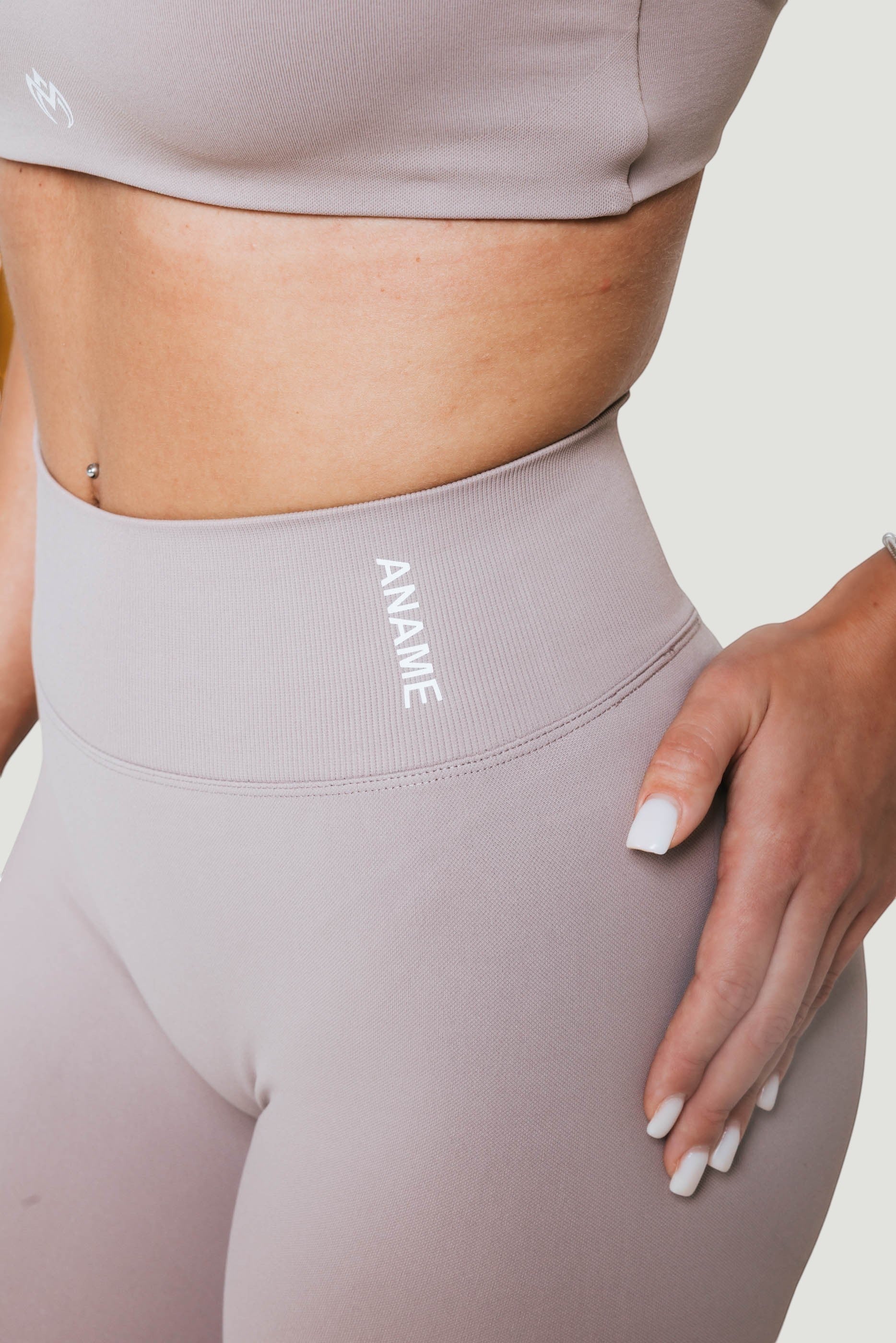 A N A M E high-waist leggings in a Mocha Cappuccino color, featuring a supportive ribbed waistband and minimalist logo.
