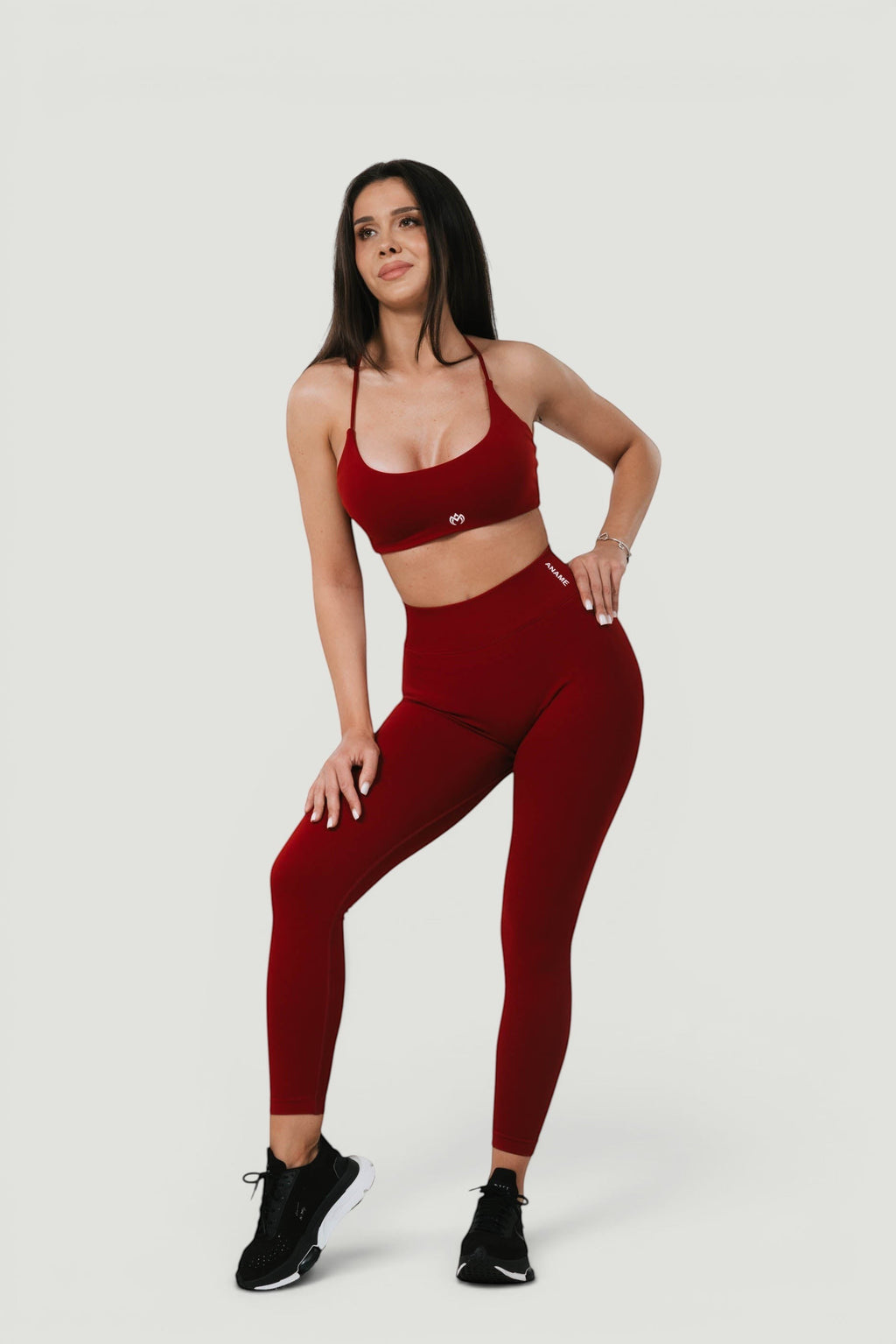 A N A M E high-waist red wine sculpting leggings worn by a model with a matching sports bra for a supportive athletic look.