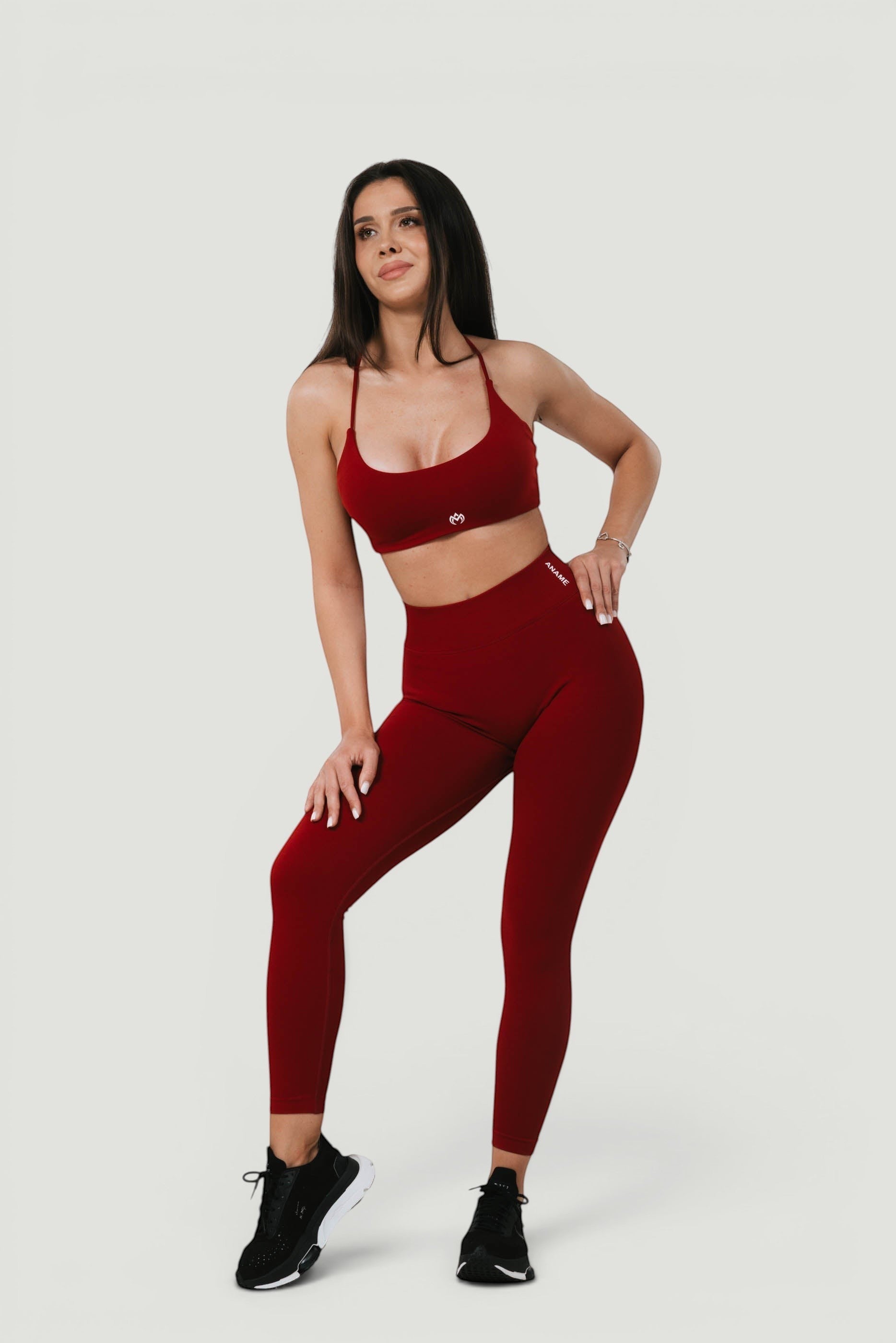 A N A M E high-waist red wine sculpting leggings worn by a model with a matching sports bra for a supportive athletic look.
