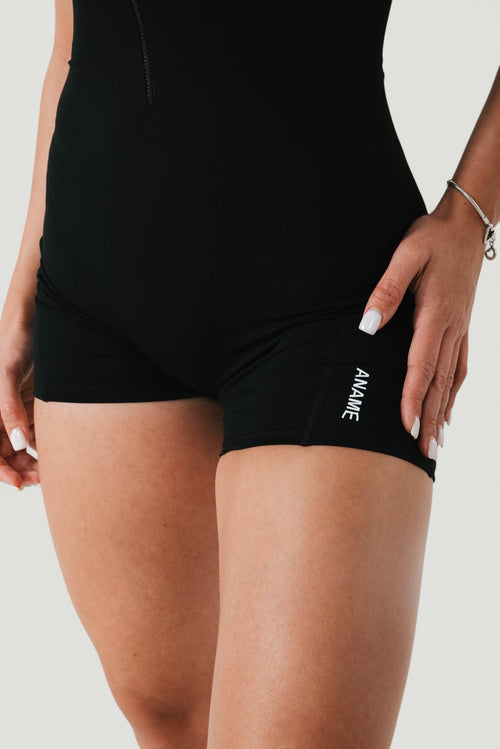 A N A M E black midnight Motion Jumpsuit featuring a stretchy, durable fabric and a subtle logo detail on the thigh.