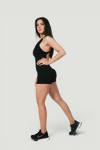 Model wearing A N A M E black midnight Motion Jumpsuit with open-back design and scrunch detail for workouts or casual wear.