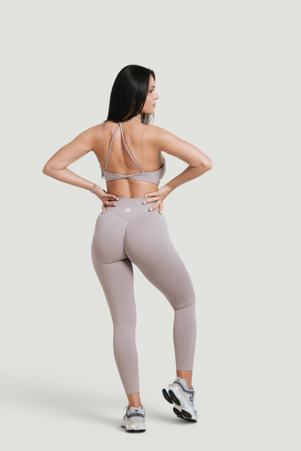 Model wearing A N A M E Mocha Cappuccino twisted-back sports bra and matching leggings for a workout.