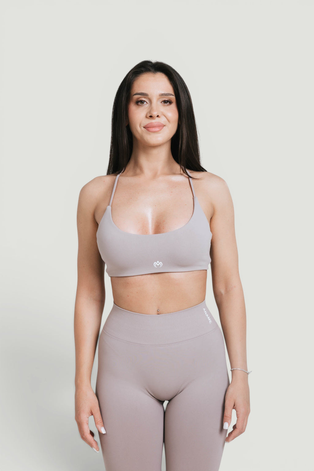 A N A M E Mocha Cappuccino sports with delicate straps and a twisted-back design worn by a model with matching leggings.