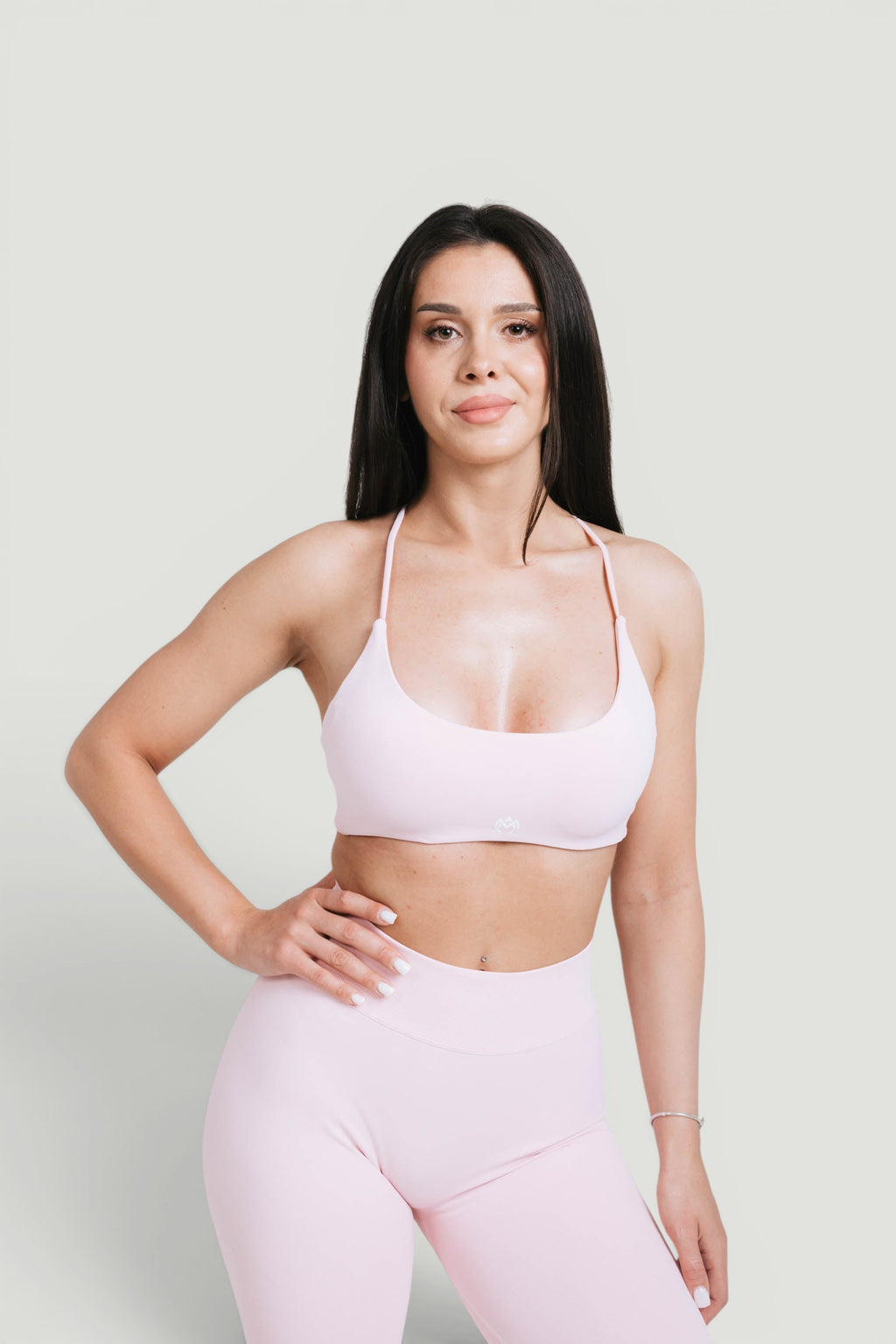 A N A M E pink rose sports bra with delicate straps on a model, designed for workout support and feminine style.