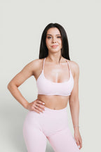 A N A M E pink rose sports bra with delicate straps on a model, designed for workout support and feminine style.